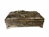 Side view of metal box showing detailed embossed architectural scenes and textured elements.