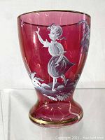 Front and side view of cranberry glass vase showing hand painted Mary Gregory style figure and landscape with gold rim accents.