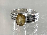 Close-up view of the front of the ring showing the yellow faceted rectangular stone set in sterling silver with beaded detailing on the band.