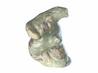 Side view of the greenish stone bear carving showing natural texture and form.