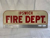 Front view of the vintage Ipswich Fire Department metal sign with red text on cream background