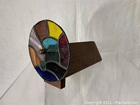 Side angled view of the wooden kaleidoscope focusing on the colorful glass lens and wood body.