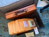 Brown leather briefcase next to a set of Manila folders on a dark wooden table
