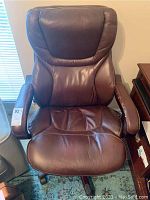 Front view of the dark brown faux leather office chair showing padded seat and backrest with minor wear.