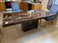 Full view of the rectangular maroon and black marble table with central pedestal base showing size and style in kitchen environment.