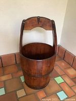 Full view of the Chinese wooden bucket with its distinctive handle, showing the rounded shape and two metal bands around the bucket.