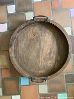 Top view of a round wooden tray showing wood grain and metal handles on sides