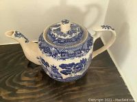 Side angle view of the Japanese blue and white porcelain kettle showing spout, lid, handle, and detailed scenic pattern.