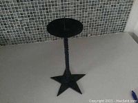 Full view of the black cast iron candle holder showing the star-shaped base and twisted stem.
