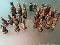 Clay chess figurines set representing Conquistadors and Incas arranged on a reflective surface, showing entire set.