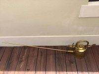 Full view of the large antique Chinese bronze kettle showing the entire length including the long spout and handle.