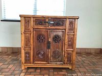 Front view showing detailed carving on drawers and main doors, metal hardware latch centralized.