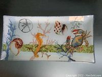 Top view of the rectangular glass tray with printed underwater sea creatures including seahorse, crab, shells, and coral.