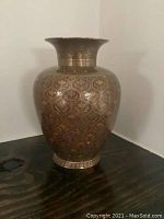 Front view of ornate brass vase showing overall shape and detailed etched Hindu patterns on its surface.