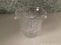 Front and side views of clear crystal ice bucket showing detailed cut glass design and handles.