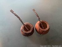 Top view of two natural gourd mate containers each containing a silver metal straw with decorative details and slight patina on gourds.