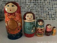 Front view of all five Matryoshka dolls arranged in size order on tile background