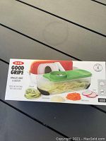 Photo of the OXO Good Grips Spiralizer container with green lid showing product packaging and spiralized vegetable example.