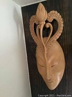 Front view of the Balinese mask showing smooth facial features and floral ornament design extending upward.