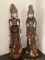 Pair of male and female Indonesian puppets standing side by side, showing full body, detailed clothing, and headdresses.
