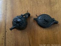 Top-down view of two small black clay kettles showing decorative lids and spouts.