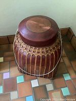 Front view of a rectangular Thai rice container with woven body and wooden lid, showing detailed woven craftsmanship and metal handle.