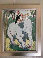 Framed Tintin reproduction print showing Tintin playing trumpet while riding an elephant with Captain Haddock and Snowy, jungle background.