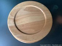Top view of a single wooden charger plate showing natural wood finish and recessed center.