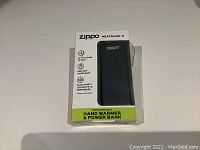 Front view of the Zippo HeatBank 3 device in its packaging showing branding and key features such as heat duration and battery capacity.