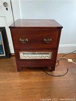 Front view of antique wooden Victrola cabinet showing drawer handles and AM/FM radio panel below.