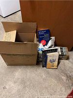 Photo of an open cardboard box and a plastic bag containing Cliff Notes along with other books.