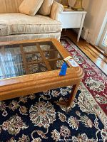 Glass top coffee table corner showing wood frame and one leg
