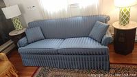 Full view of the blue striped fabric sofa with cushions, showing overall condition and design.