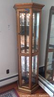 Front and side views of tall wooden curio cabinet with glass shelves and mirrored back panels