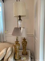 Photo of the hanging ceiling lamp and two matching table lamps. The ceiling lamp has a large pleated shade, crystal and brass body on a chain. The table lamps have floral ceramic bases with different shades.