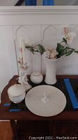 Full view of all items on wooden table including vase, candlesticks, serving dish, and covered bowls