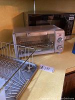 Toaster oven in front of a black Panasonic microwave; both on kitchen counter