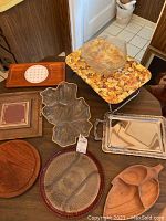 Overview of platters and trays including a floral TV tray, glass leaf tray, silver plated tray, wooden trays, and a covered glass bowl