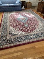 Full view of the rug showing red central area with a floral design and surrounding borders.