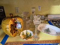 Photo showing a yellow ceramic cookie jar with olive branch design, Reichenbach small decorative bowl with lemon motif, Nikko holiday platter with pine tree decoration, and two crystal glass candlesticks.