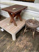 Photo showing smaller wooden table with cross legs and wicker stool next to a wall