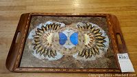 Full view of wooden serving tray with butterfly and floral design on tray surface, wood inlay edges visible, handles shown