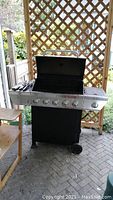 Full view of Nexgrill 5 burner barbecue with side burner and wheels, placed on patio.