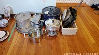 Full lot overview showing all cookware items including large blue enamel canning pot, metal pots with lids, and kitchen accessories in bin.