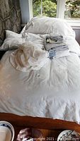 White patterned duvet cover, pillow cases, and blankets arranged on a single bed.