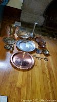 Photo showing all metalware items laid out on the floor including plates, bowls, bells, a tall vase, and wall hook.