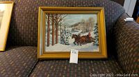 Framed winter scene oil painting showing bare trees and horse sled in snow.