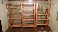 Front view of two attached wooden shelving units with multiple shelves and rugged construction in basement space.