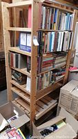 Two adjacent wooden shelving units filled partially with books and boxes showing size and condition.