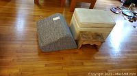 Photo showing the cream storage ottoman, gray wedge cushion, and small wooden stool placed on hardwood floor, highlighting their condition and size.